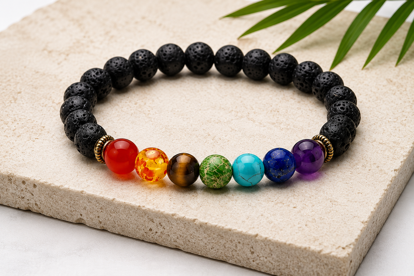 A beaded chakra bracelet made of black lava stones with seven colorful gemstone beads representing the chakras, displayed on a light stone slab.